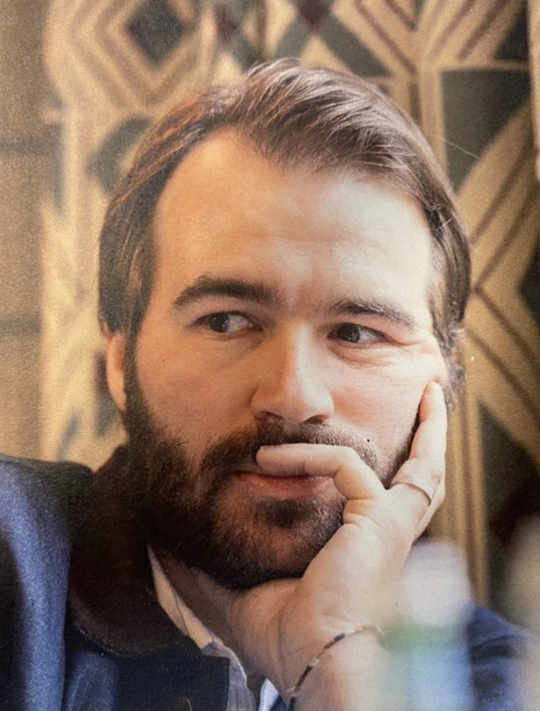 Thijs has brown hair and a beard. He is looking thoughtful and rests his head in his hands. 
